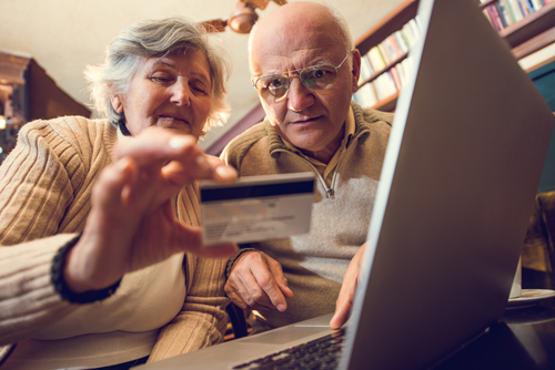 Below view of senior couple home shopping with credit card.