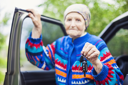 Senior woman holding car key and smiling, selective focus