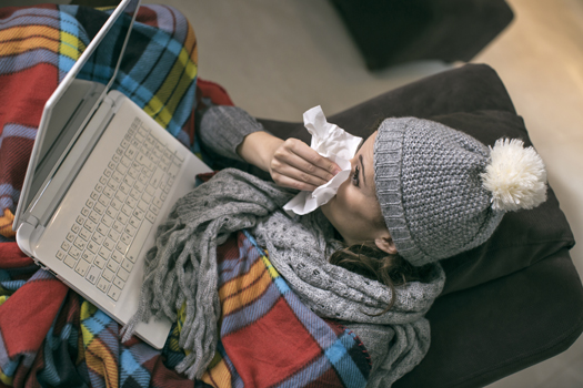 Young woman which has a flu working from home on a laptop