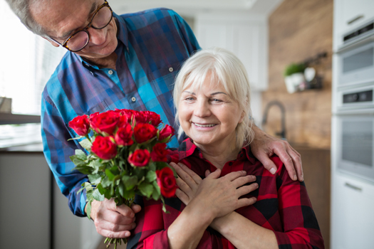 Portrait of senior woman surprised by her husband with roses