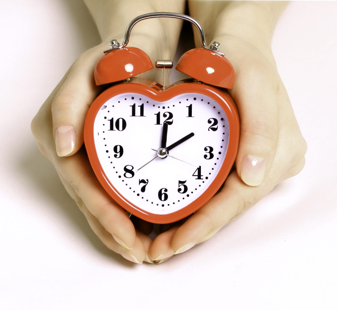 red heart-shaped clock in a woman's hands