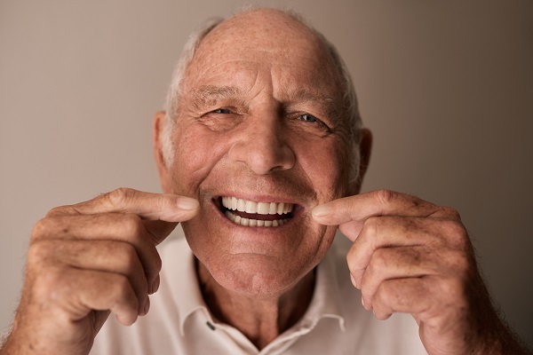 Closeup portrait of an ecstatic senior man pointing at his a big toothy grin while sitting at home
