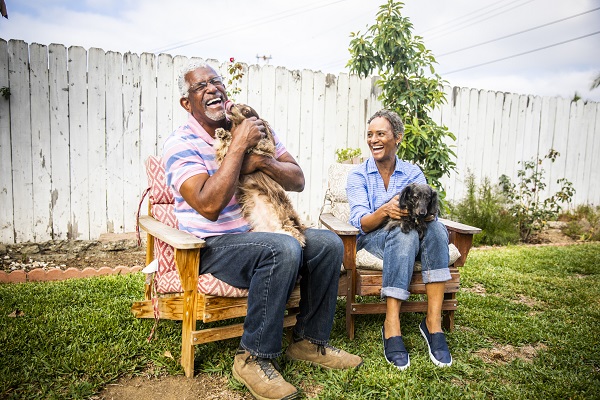 A senior black couple playing outdoors with their two dachshunds