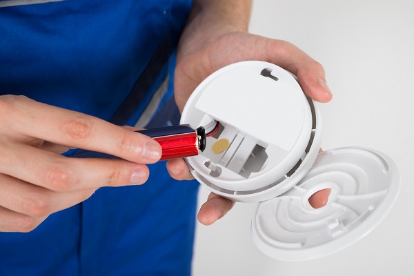 Close-up Of Electrician Hand Holding Battery Of Smoke Detector