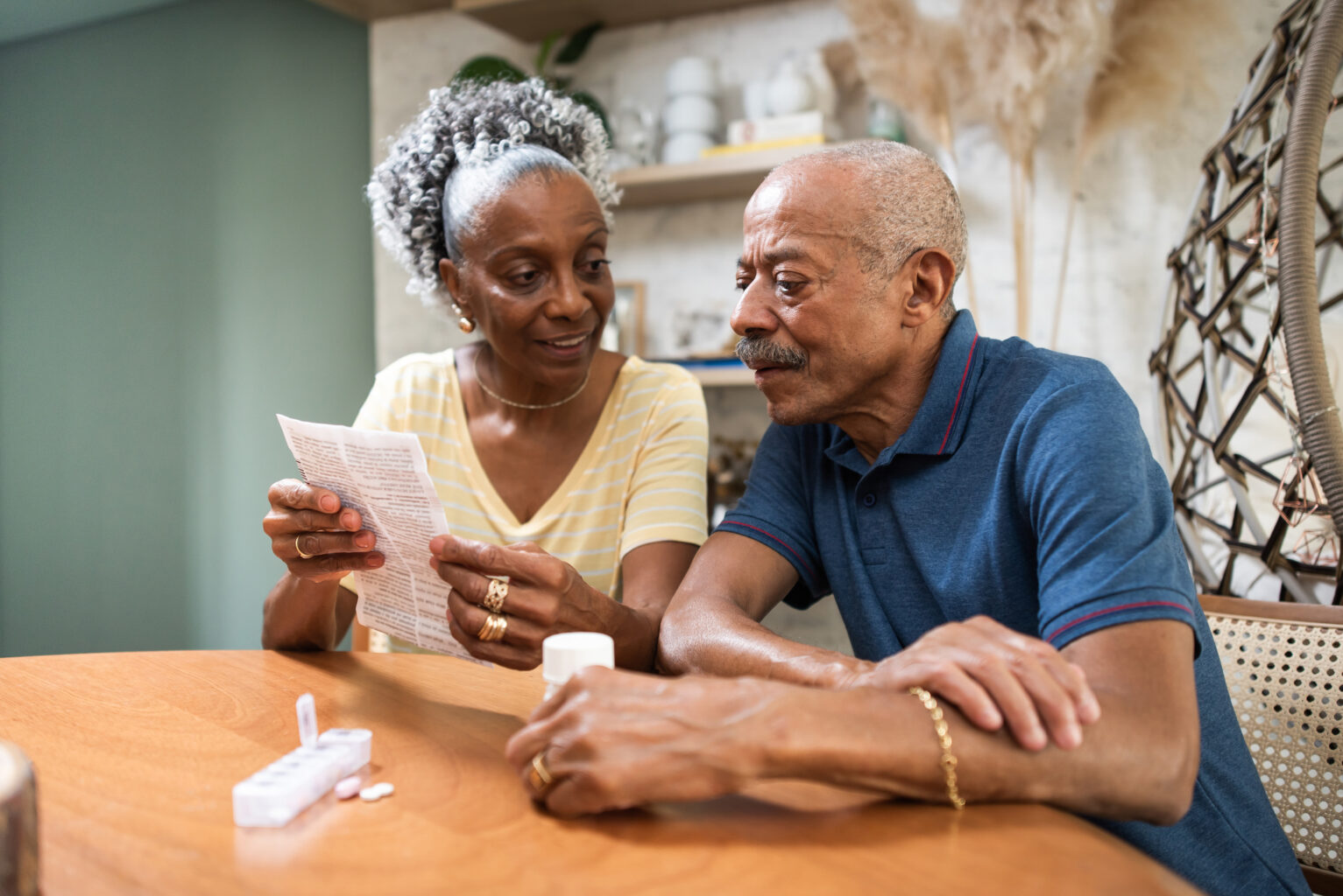 black senior couple sitting at table reading medication instructions