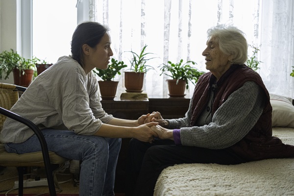 Volunteer woman caretaker talking with senior woman.