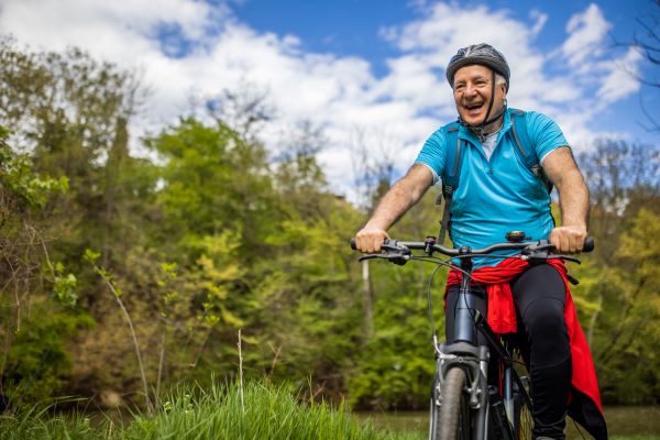 Older adult man smiles while riding a bike in the great outdoors