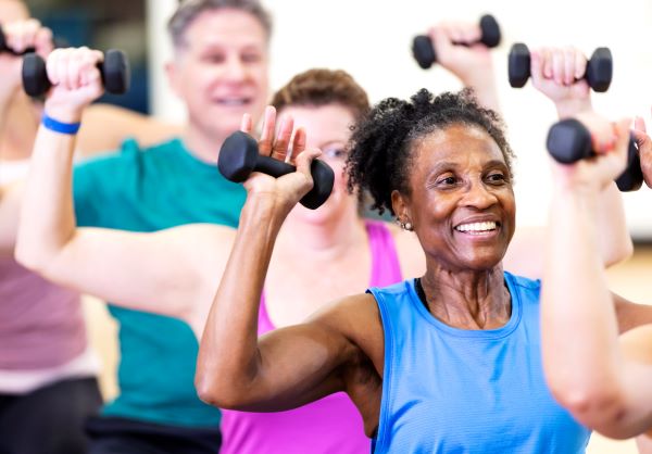 Older adults lift dumbbells in a group strength training class