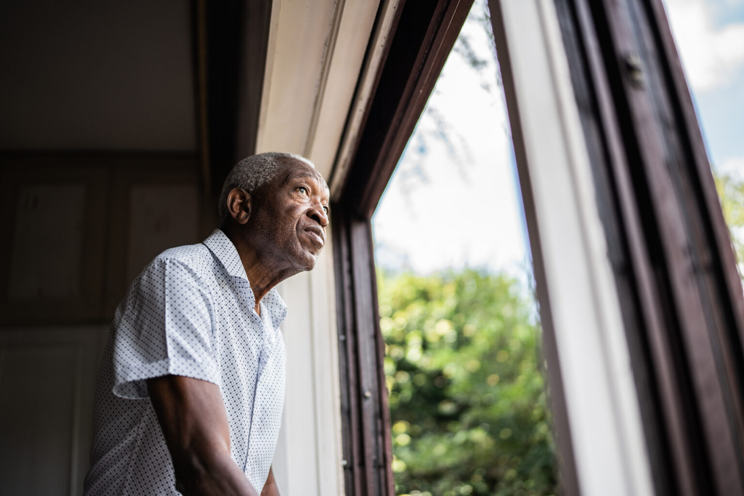 Senior man contemplating looking through the window
